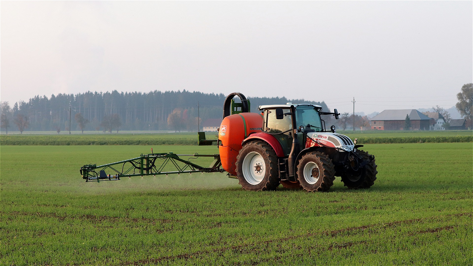 Red tractor in a field spraying crops